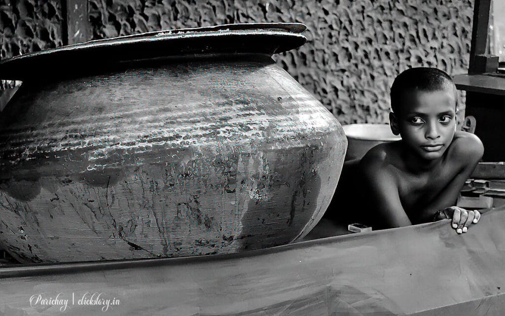 a boy staring at rice pot street photography