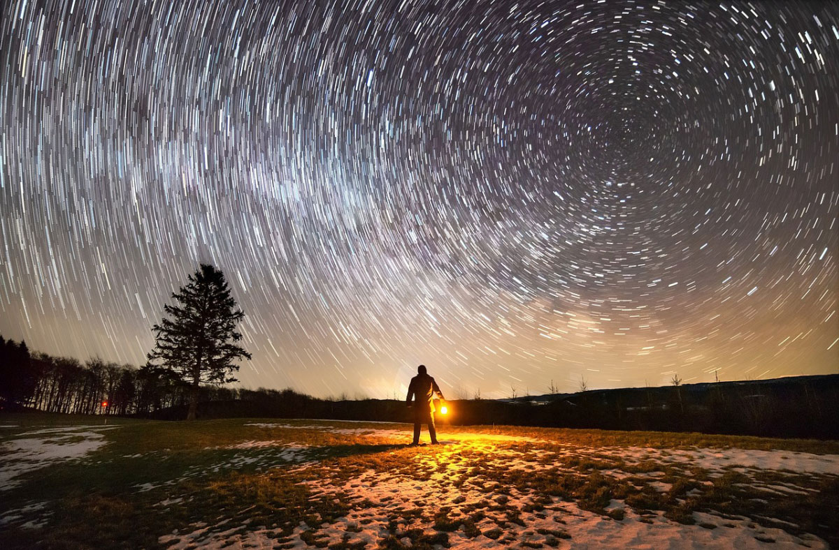 star trails and man with light